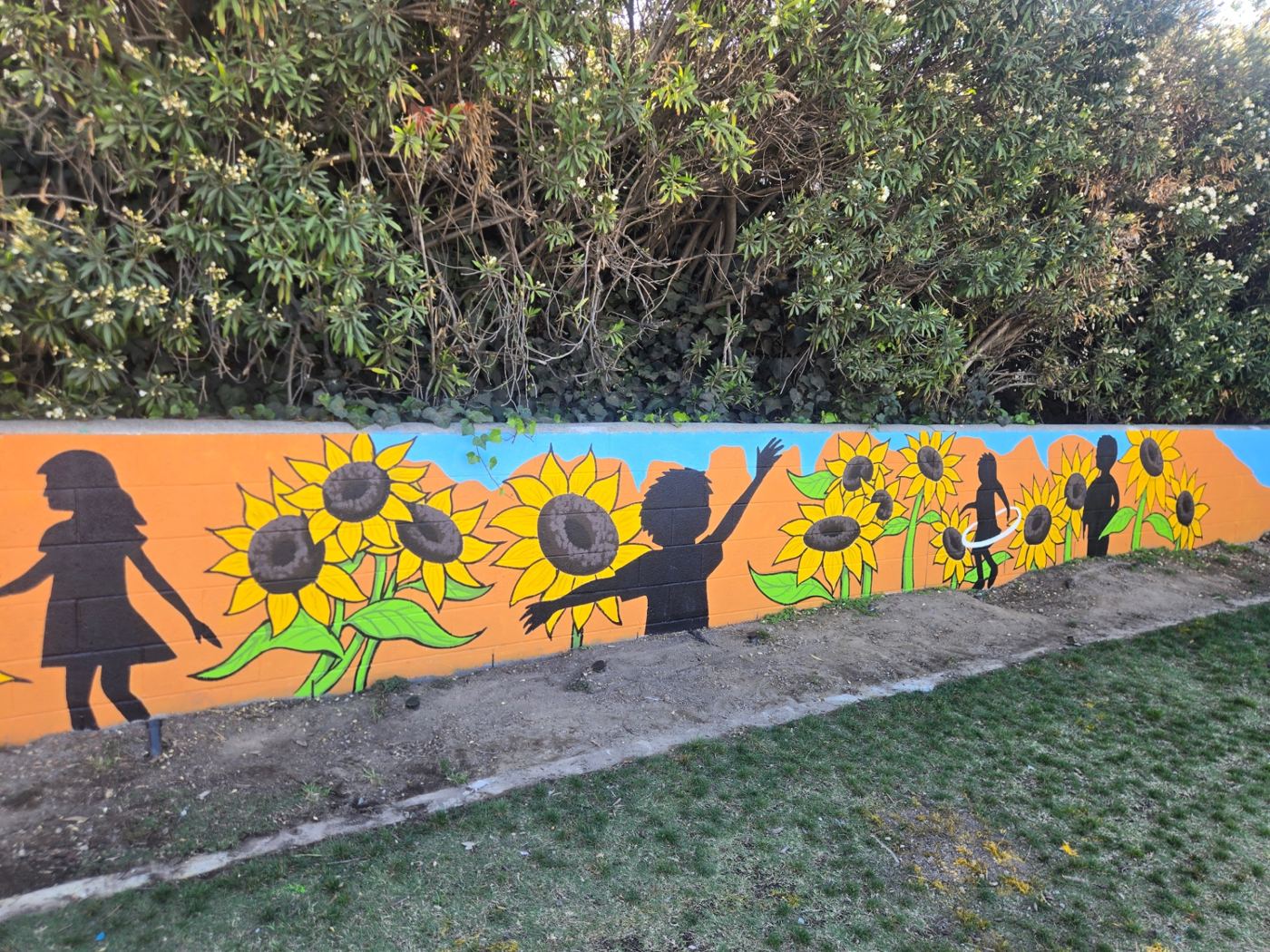Sunflowers and playing children painted on a block wall