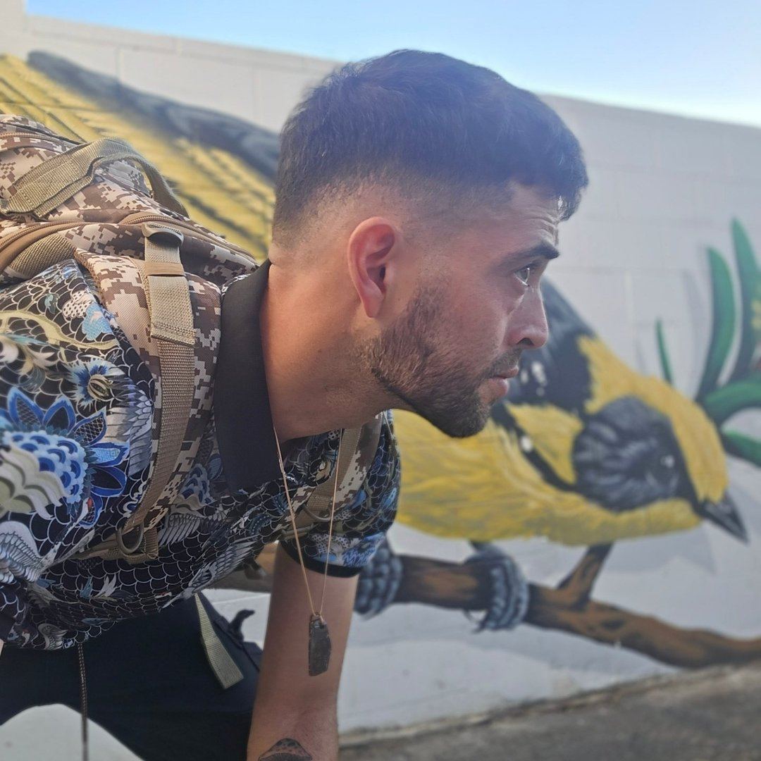Portrait of muralist Carlos Rodriguez holding paint brushes