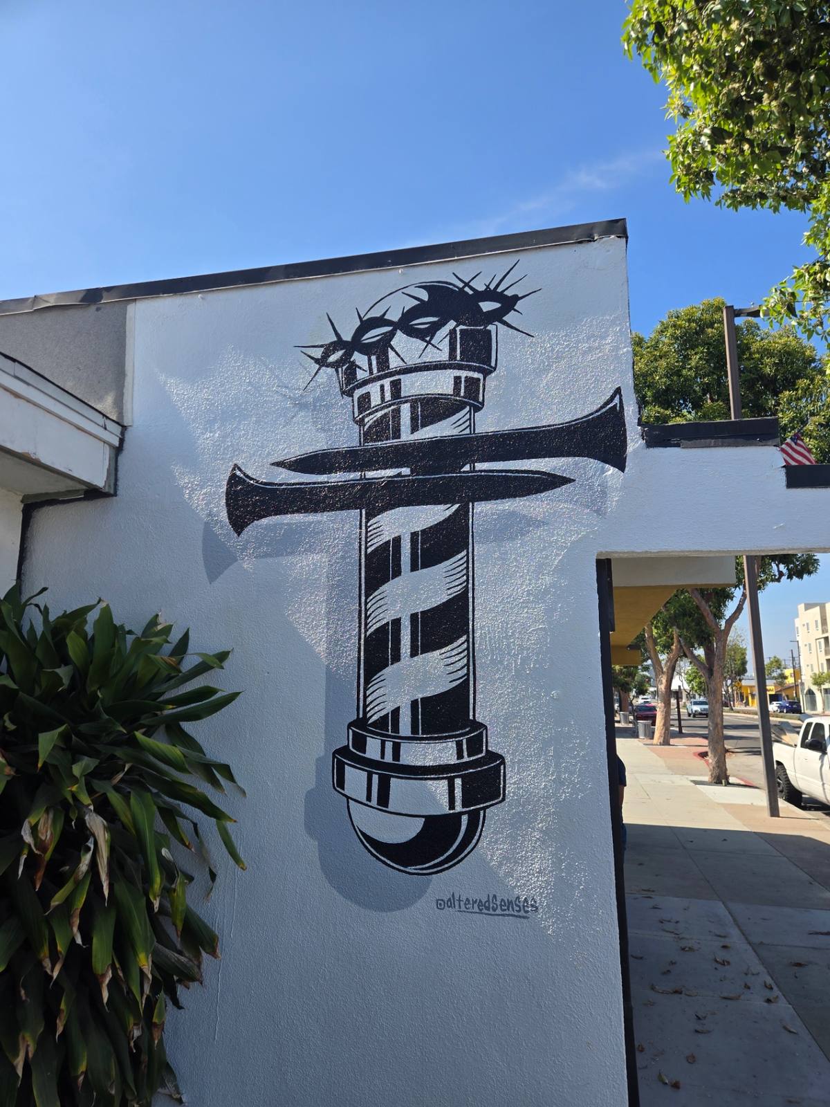 Hand-painted barber pole cross with crown of thorns on a faith-themed business exterior wall