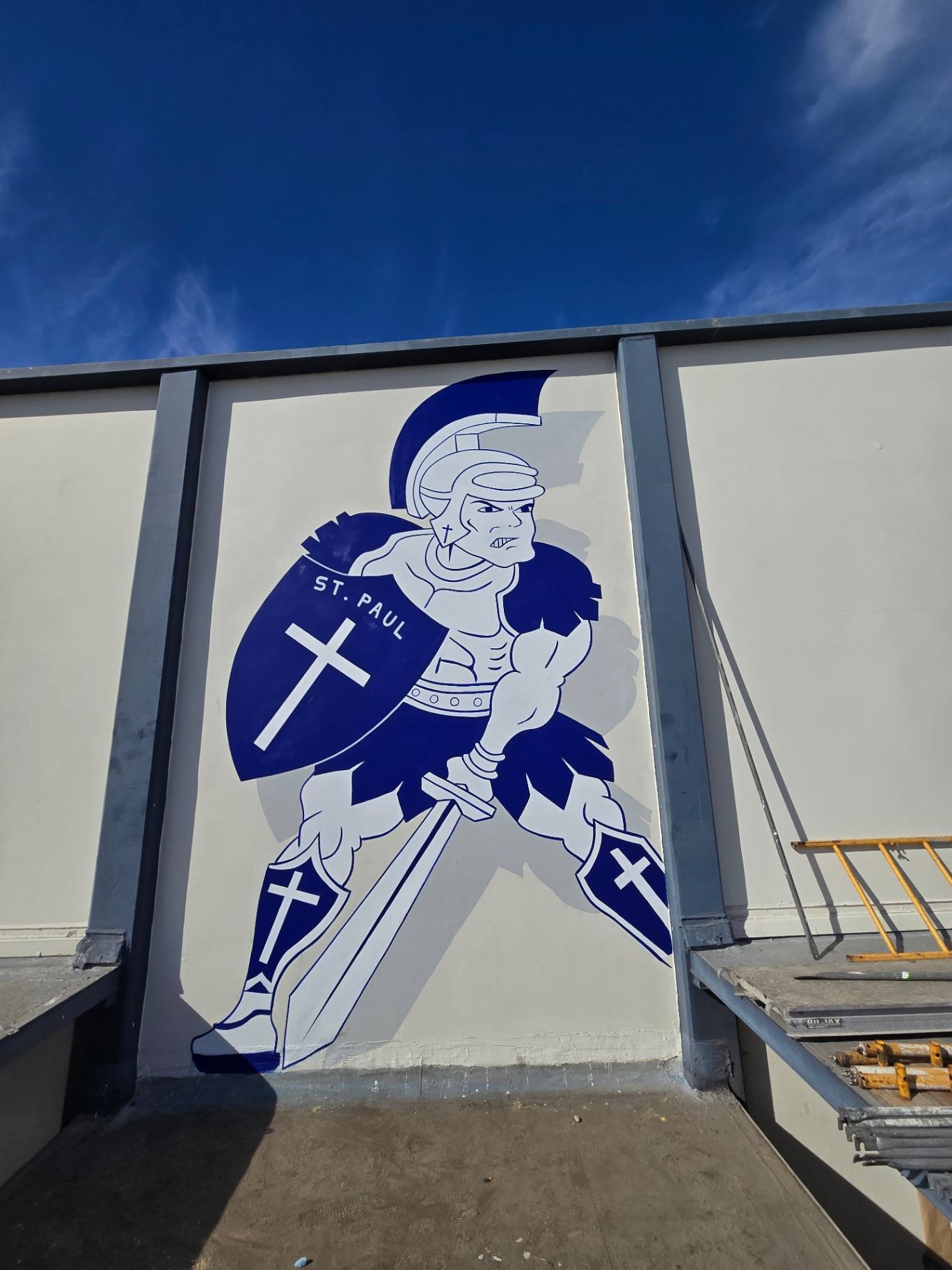 Navy and white St. Paul knight mascot with a cross shield painted on a school wall